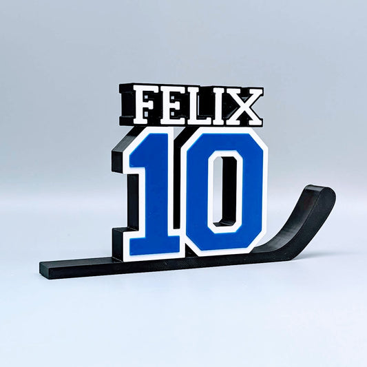 Personalized hockey jersey number nameplate "FELIX 10" in blue, white and black on a hockey stick