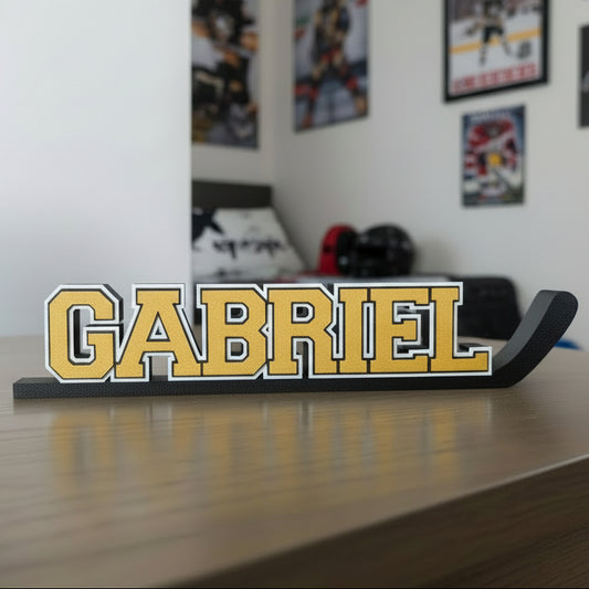 Hockey stick nameplate "GABRIEL" in gold and black in a hockey fan bedroom