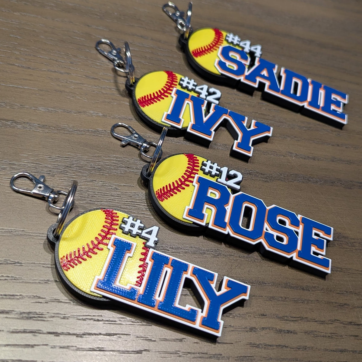 Four softball bag tags with numbers: SADIE #44, IVY #42, ROSE #12, LILY #4