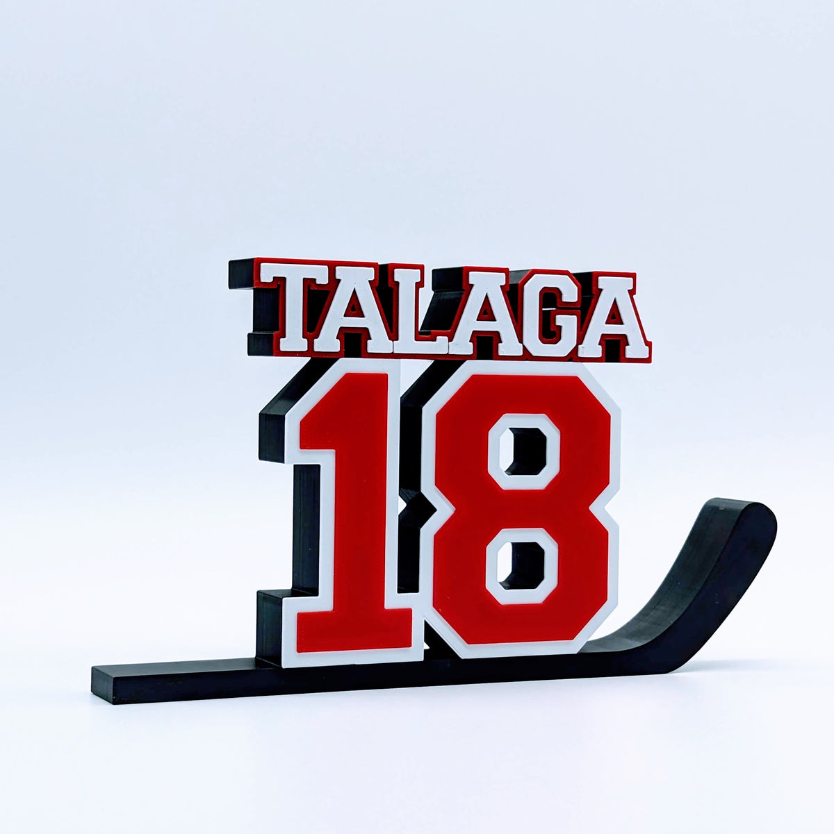 Personalized hockey jersey number nameplate "TALAGA 18" in red, white and black on a hockey stick