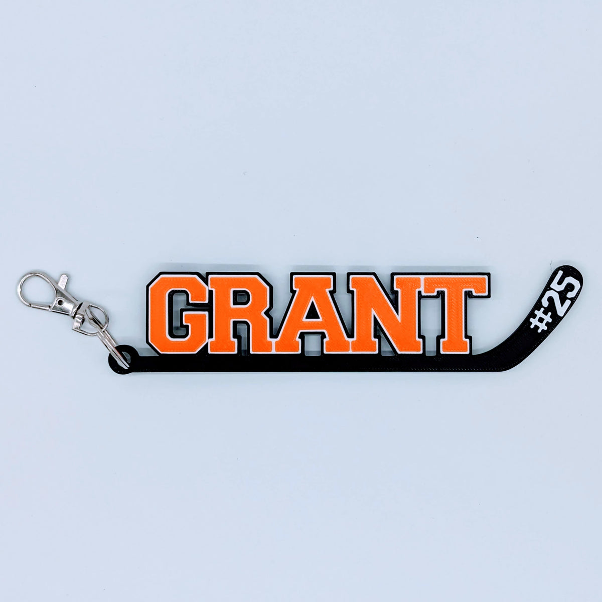Hockey stick bag tag "GRANT #25" in orange and black with metal clip