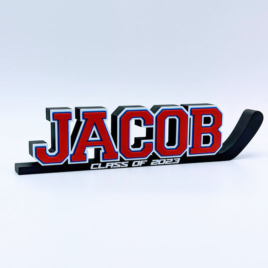 Hockey stick nameplate "JACOB" in red, white and blue with "Class of 2023"