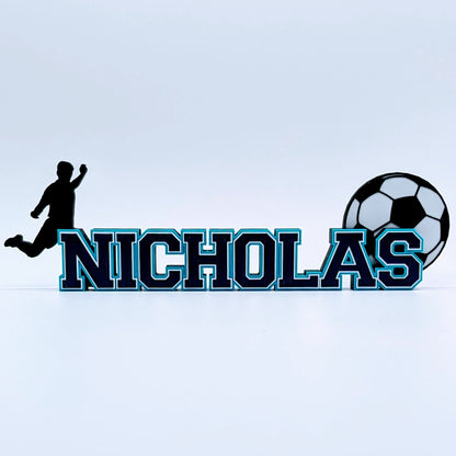 Long soccer name sign "NICHOLAS" in navy and light blue with soccer ball