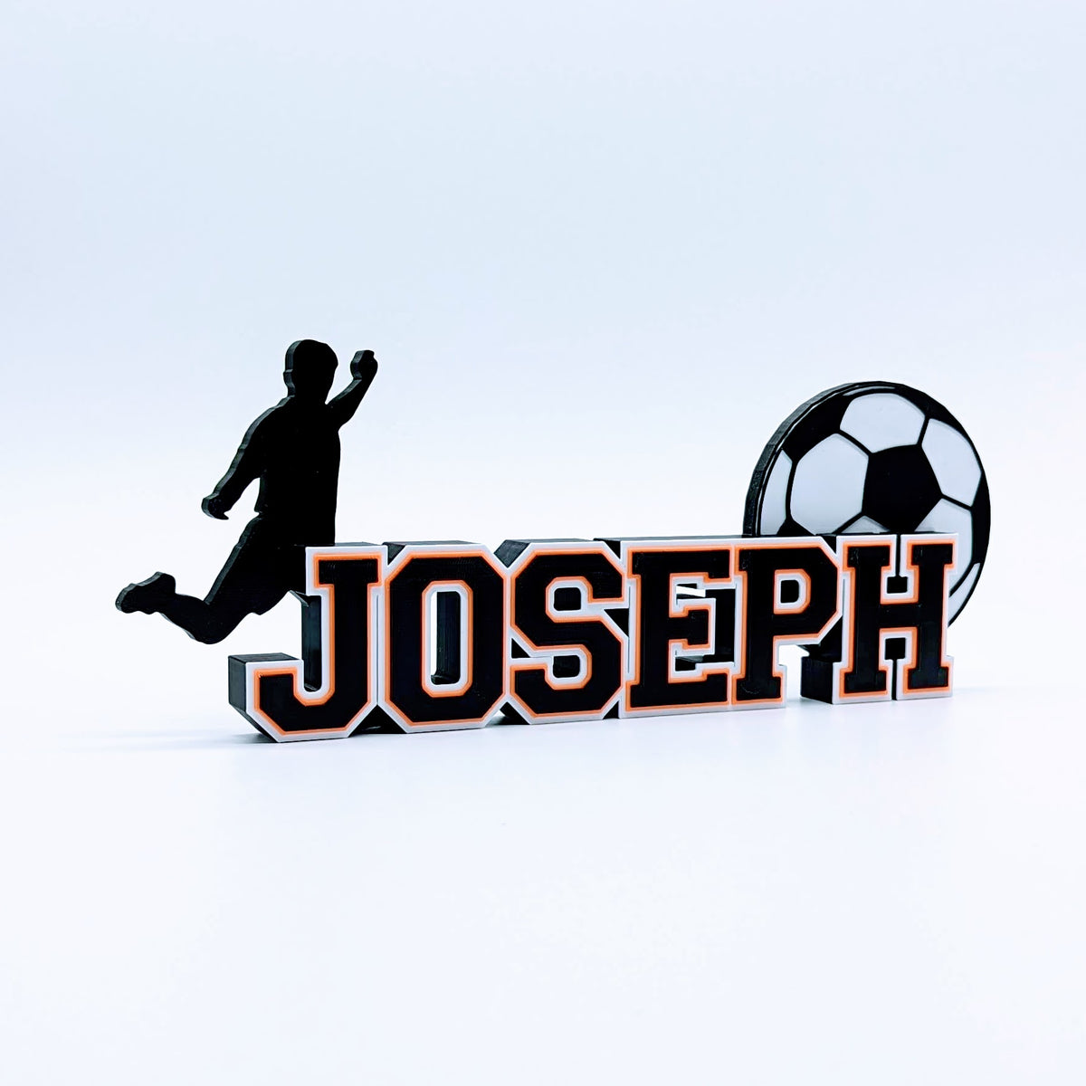 Personalized soccer nameplate "JOSEPH" in black and orange with player silhouette and soccer ball