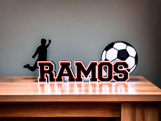 Soccer nameplate "RAMOS" in red and black on a wooden shelf