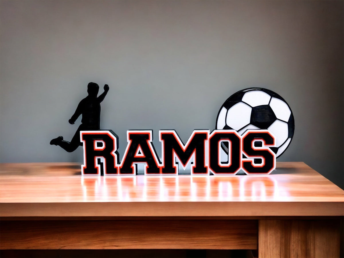 Soccer nameplate "RAMOS" in red and black on a wooden shelf