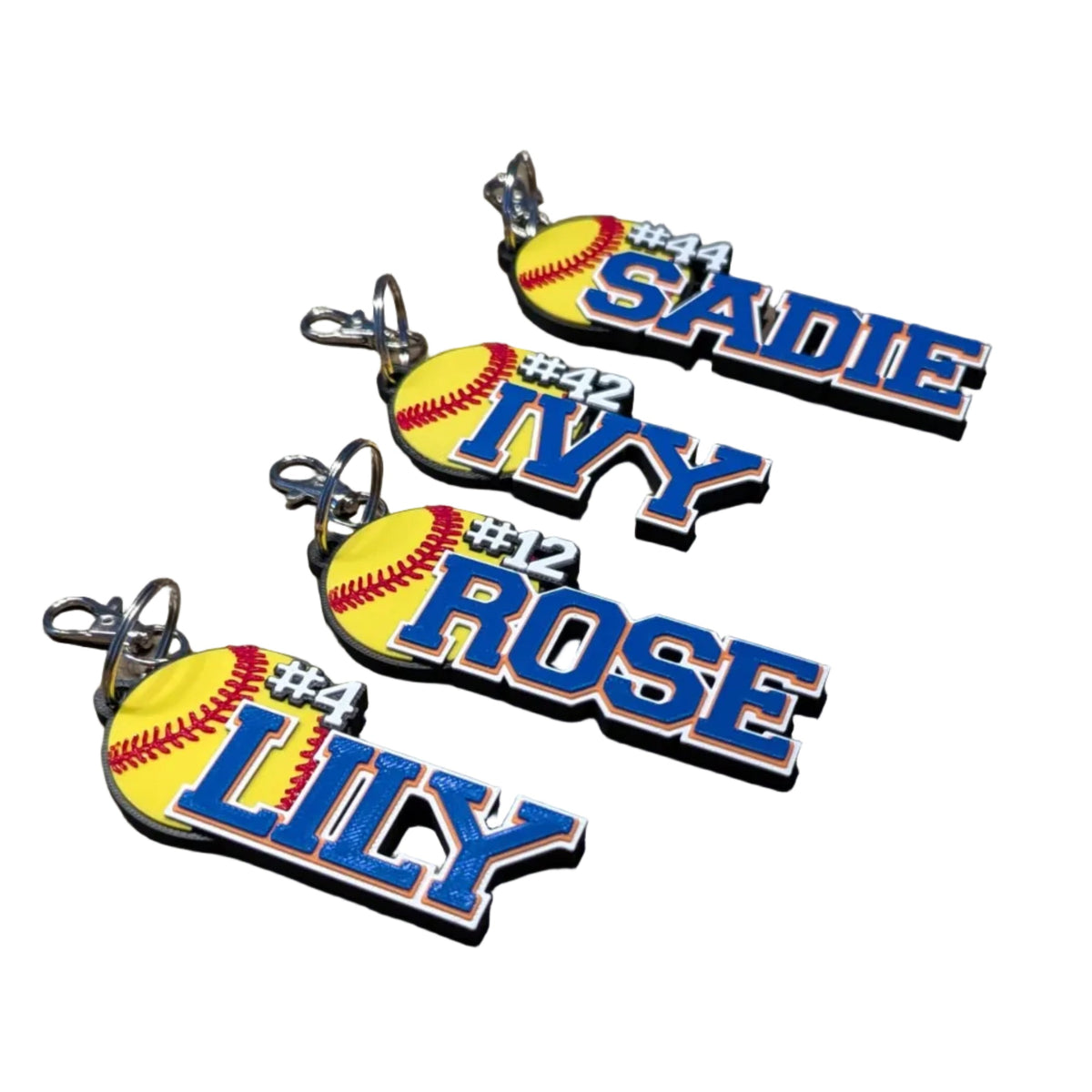 Three personalized softball keychains with player names on a white surface