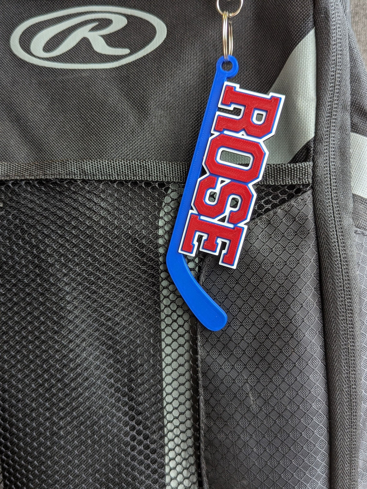 Blue hockey stick bag tag "ROSE" in red and white on a backpack