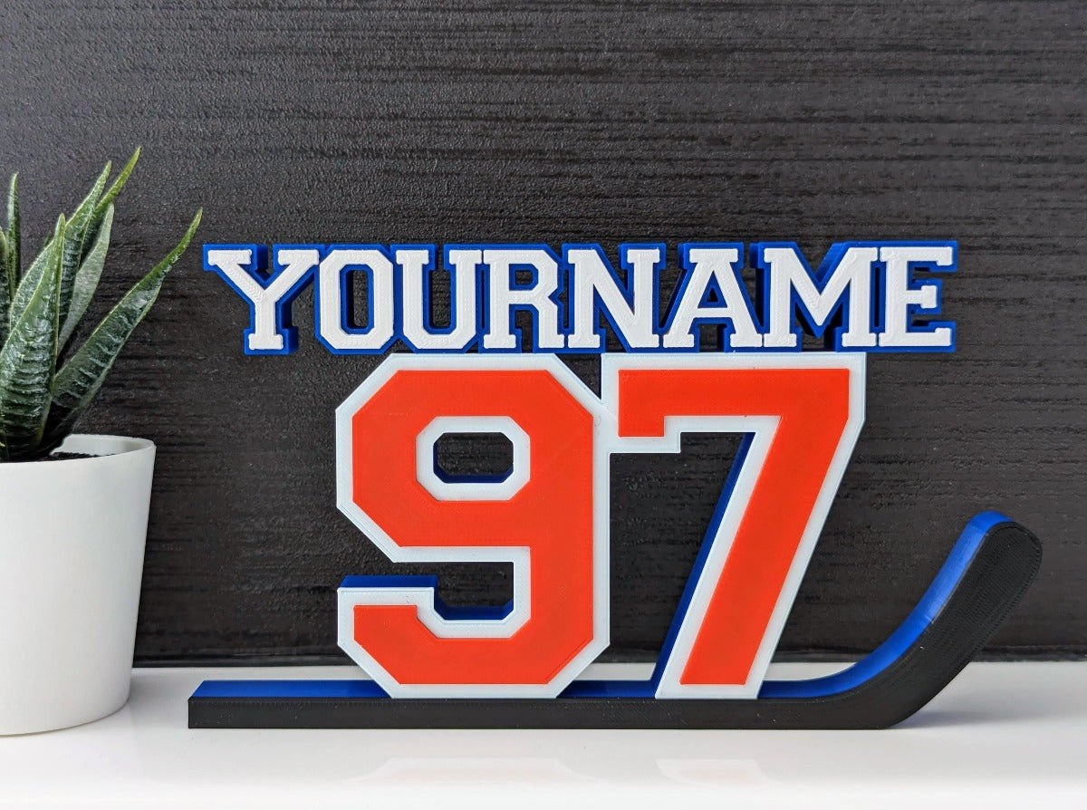 Personalized hockey jersey number nameplate "97" in orange, blue and white on a bedroom shelf