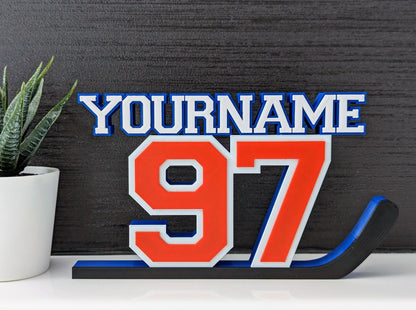 Personalized hockey jersey number nameplate "97" in orange, blue and white on a bedroom shelf