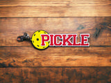 Pickleball bag tag "PICKLE" in red with yellow pickleball on wood